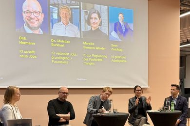 Five speakers are sitting on the stage during the panel discussion