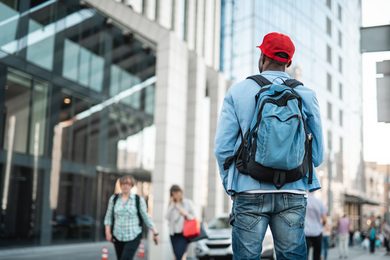 Mann mit Rucksack vor Gebäude